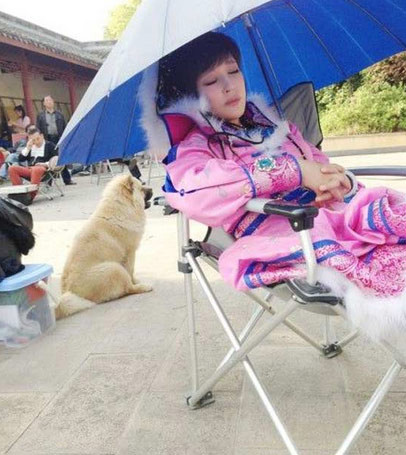 Lưu Hiểu Khánh che dù ngồi ngủ giữa sân nắng vì quá mệt sau một cảnh quay.
