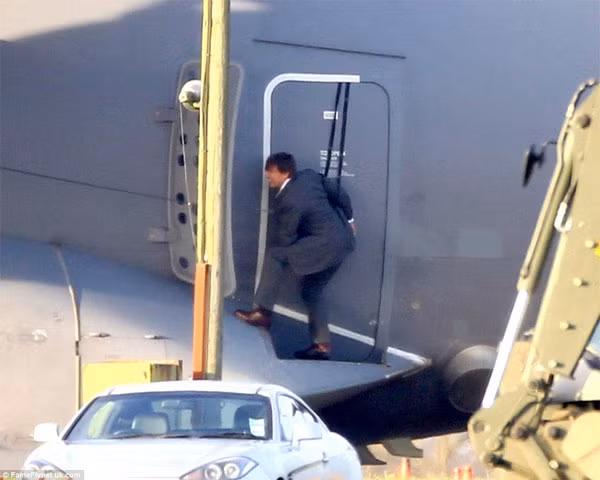 Tom mặc bộ vest tối màu, chuẩn bị cho cảnh quay mạo hiểm trên cao với chỉ hai dây bảo hiểm móc vào người.