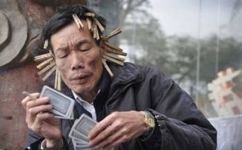 Một người đàn ông đánh bài bị cặp xung quanh đầu - một loại hình phạt khi bị thua tại công viên thành phố Trung Sơn, tỉnh Quảng Đông.