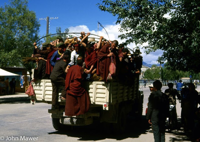 Các nhà sư và người lao động chen chúc trên xe tải để đến nơi làm việc, học tập.