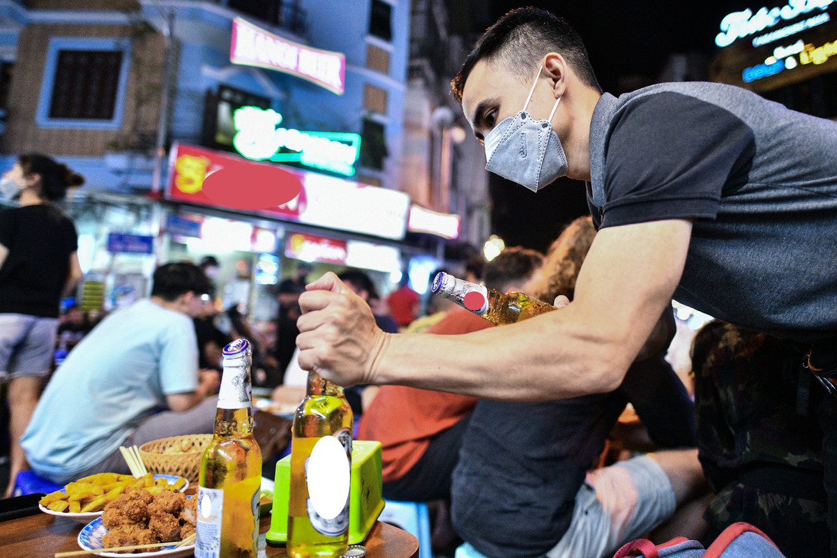 Chủ một quán bia liên tục mở đồ uống cho khách. "Quán tôi nằm ngay ở vị trí ngã tư đắc địa nên đông đúc, khách lui tới liên tục nên từ khoảng 21h lúc nào bàn cũng kín chỗ", anh chia sẻ.