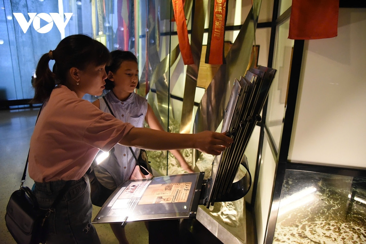 Khách tham quan lật giở từng quyển sách mở (tuốc-ni-kê) để hiểu rõ hơn về cuộc đời cách mạng của Chủ tịch Hồ Chí Minh.