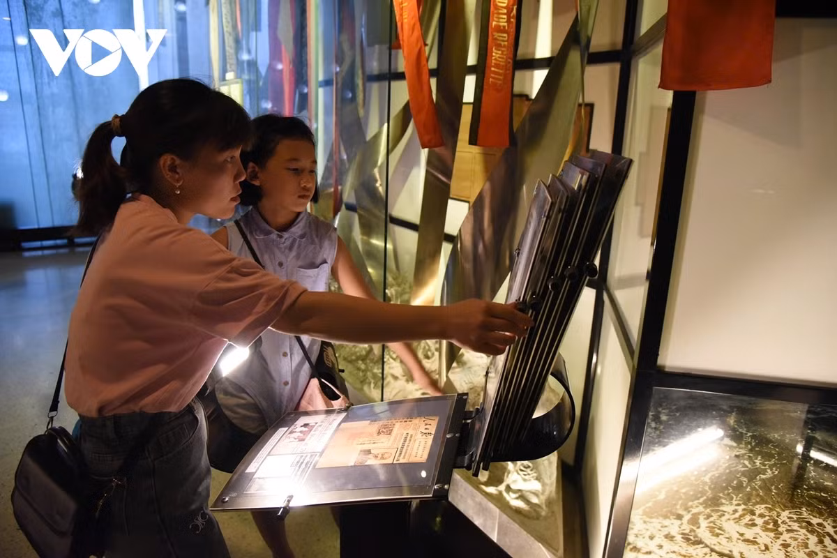 Khách tham quan lật giở từng quyển sách mở (tuốc-ni-kê) để hiểu rõ hơn về cuộc đời cách mạng của Chủ tịch Hồ Chí Minh.