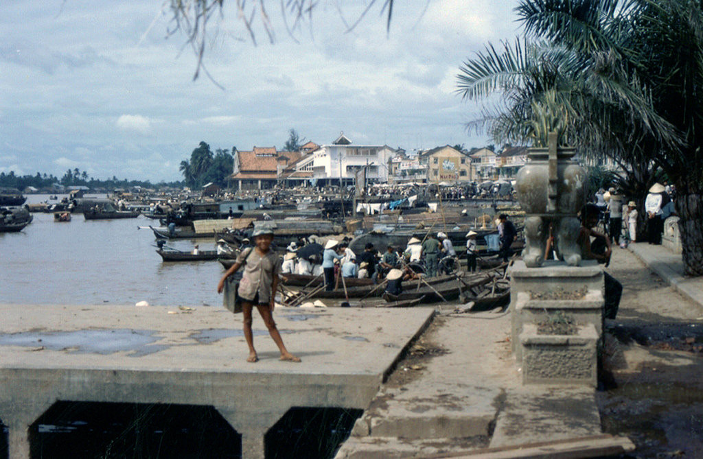 Cậu bé đứng trên cầu tàu ở bến Ninh Kiều, phía xa là chợ Cần Thơ, cuối thập niên 1960. Ảnh: James M. Kraft.