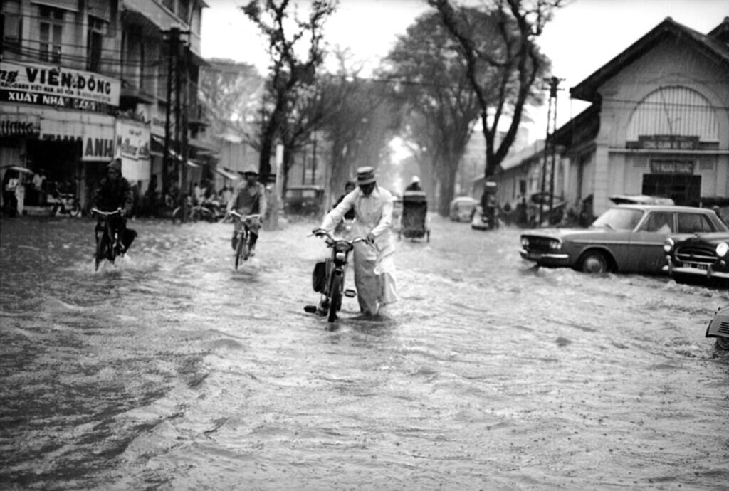 Chiếc xe không chạy nổi, một người đàn ông phải dắt xe qua ngã tư Lê Lợi - Parteur. Ảnh: Eddie Adams.