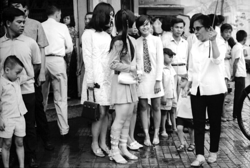 Người dân chờ mưa tạnh dưới mái hiên của một tòa nhà. Ảnh: Eddie Adams.