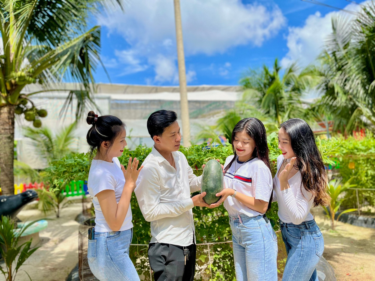 Bạn Bảo Hiếu tạo dáng cùng nhóm bạn nữ bên trái cây vừa thu hoạch được. "Tôi ấn tượng với vườn dưa đa chủng loại này. Lần đầu tiên tôi biết tới giống dưa hấu Ngọc Bích vỏ xanh bóng căng tròn, ruột vàng ươm, vị ngọt thanh mát lạnh. Đặc biệt hơn còn có cả đu đủ Mexico, táo xanh Thái Lan, dừa xiêm, ổi Ruby Đài Loan...", Hiếu hồ hởi kể.