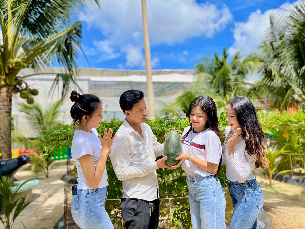 Bạn Bảo Hiếu tạo dáng cùng nhóm bạn nữ bên trái cây vừa thu hoạch được. "Tôi ấn tượng với vườn dưa đa chủng loại này. Lần đầu tiên tôi biết tới giống dưa hấu Ngọc Bích vỏ xanh bóng căng tròn, ruột vàng ươm, vị ngọt thanh mát lạnh. Đặc biệt hơn còn có cả đu đủ Mexico, táo xanh Thái Lan, dừa xiêm, ổi Ruby Đài Loan...", Hiếu hồ hởi kể.