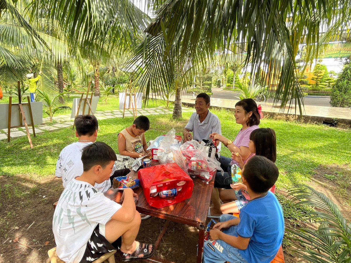 Một gia đình may mắn "xí" được chỗ ăn uống mát mẻ bên dưới những tán dừa.