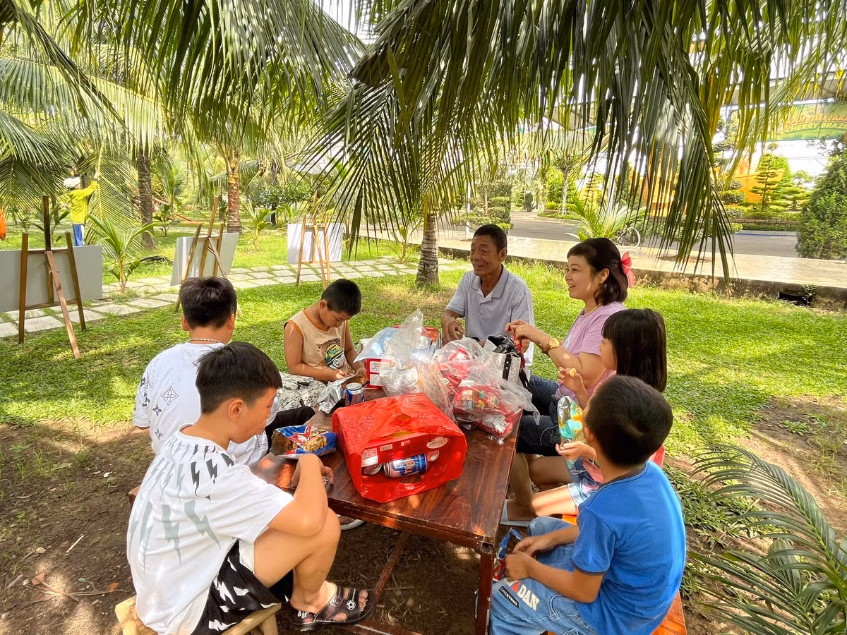 Một gia đình may mắn "xí" được chỗ ăn uống mát mẻ bên dưới những tán dừa.