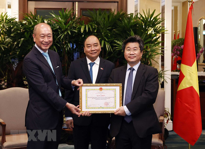 Chủ tịch nước Nguyễn Xuân Phúc chứng kiến lễ trao tặng Bằng khen của Bộ trưởng Bộ Kế hoạch và Đầu tư Việt Nam cho Ngân hàng UOB. Ảnh: TTXVN