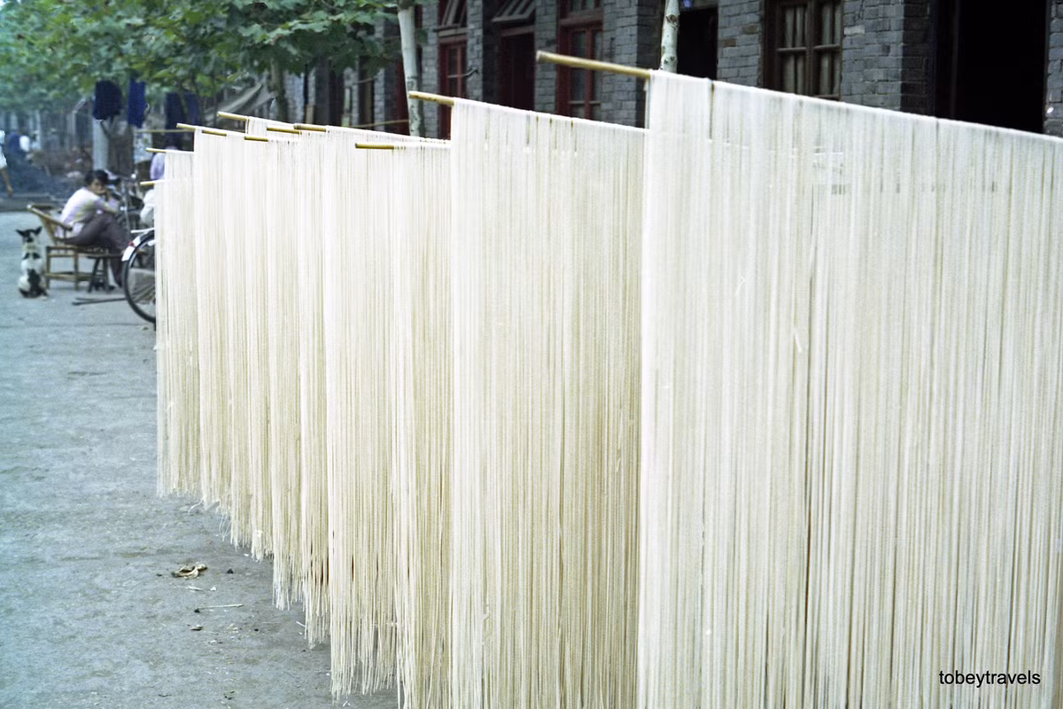 Mì làm thủ công được phơi trên sào tre bên ngoài một ngôi nhà.