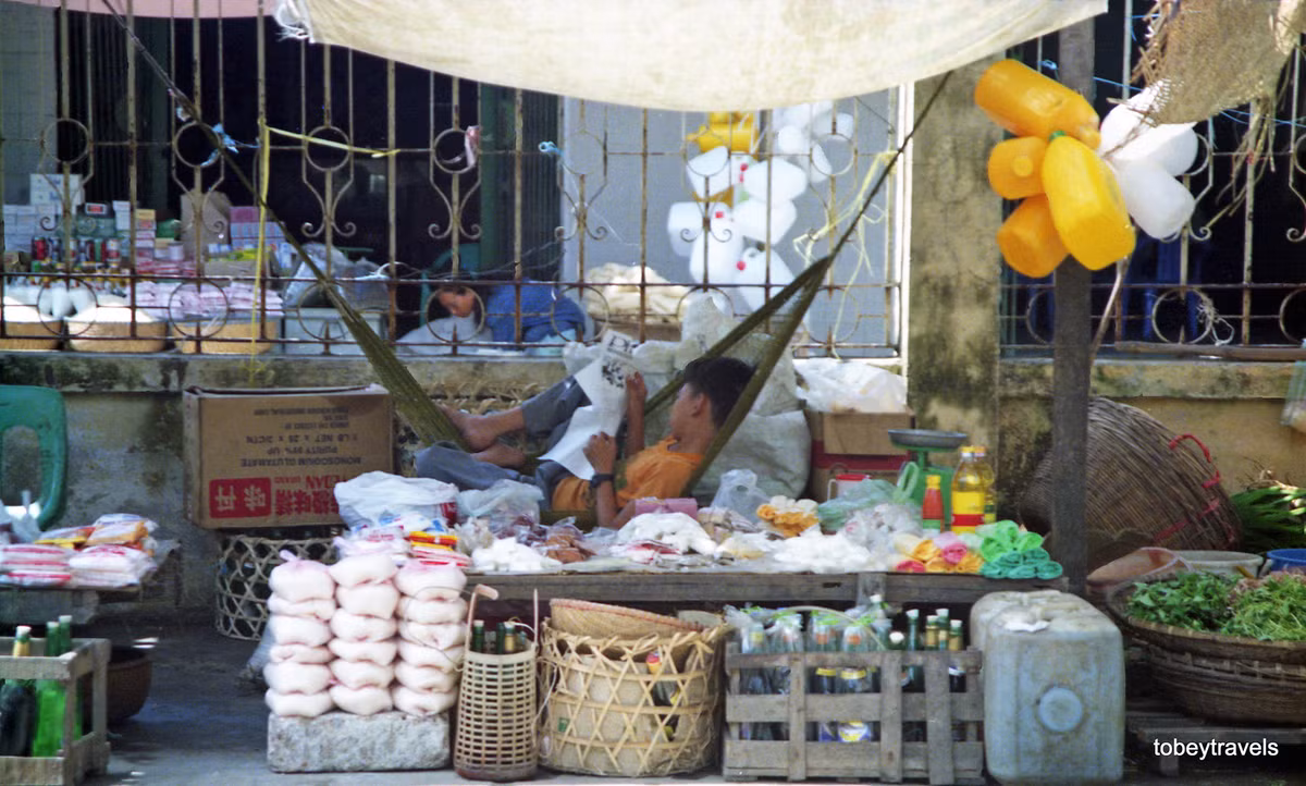 Một cậu bé nằm võng khi trông cửa hàng.