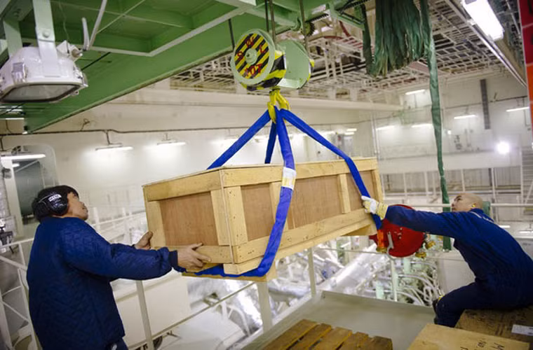 Các thủy thủ dùng tờ để đưa một thùng đựng phụ tùng vào phòng động cơ trên tàu Maersk Mc-Kinney Moeller.