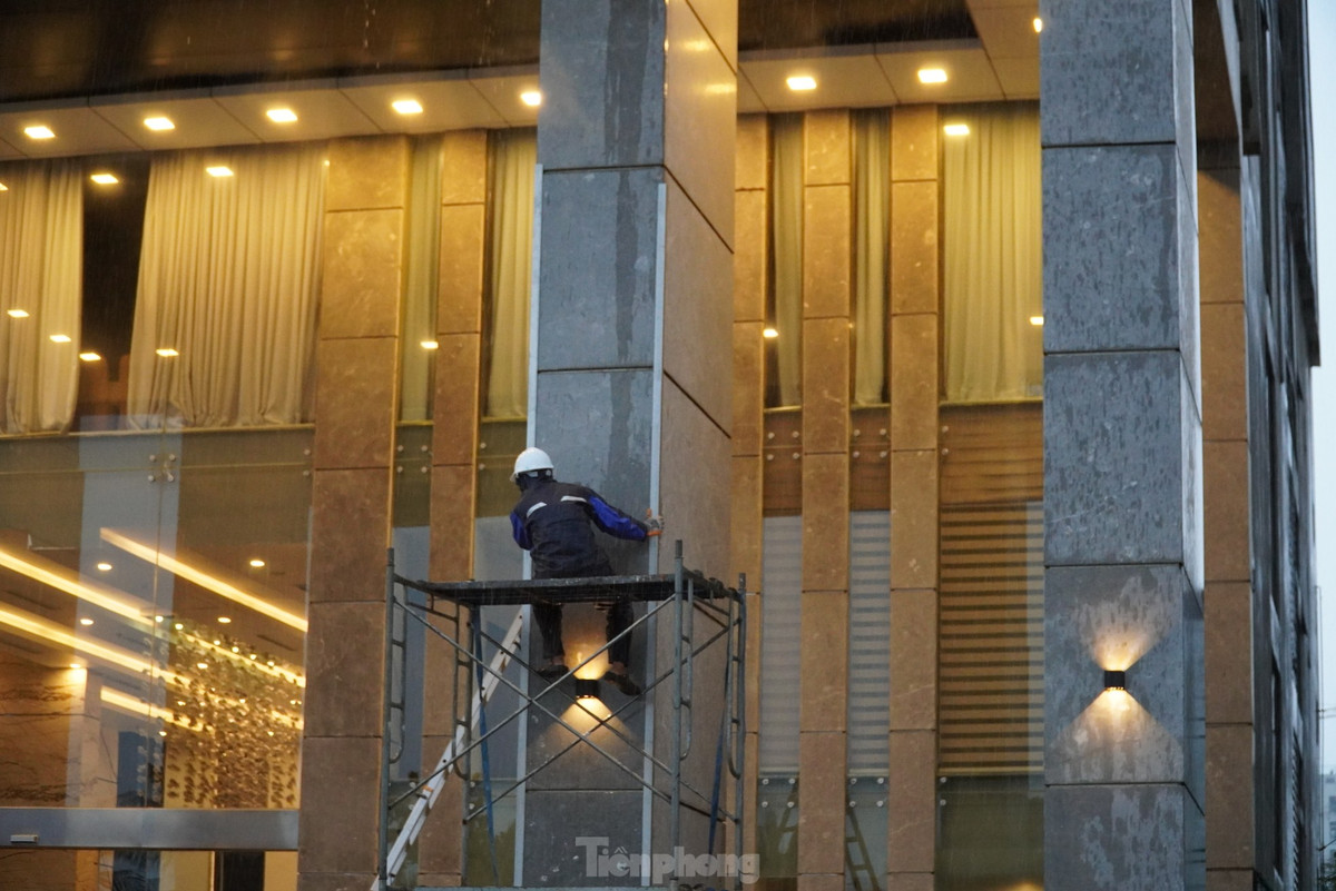 Nhân viên một khách sạn leo lên giàn giáo chuẩn bị chèn chống mặt tiền dưới trời mưa to. Dự báo sáng 27/10, các quận Sơn Trà, Ngũ Hành Sơn, Thanh Khê, Liên Chiểu, Hải Châu và Cẩm Lệ có gió mạnh dần lên cấp 6-7, vùng gần tâm bão đi qua gió mạnh cấp 8, giật cấp 11.