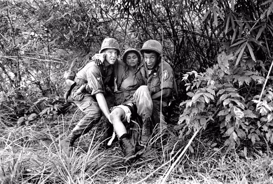 Hai lính quân y Mỹ là Gerald Levy (bên trái ảnh, đến từ New York) và PFC Andre G. Brown (bên phải ảnh, đến từ Chicago) dìu đồng đội bị thương tới một máy bay trực thăng để sơ tán ra khỏi vùng chiến sự trong thời gian diễn ra cuộc chiến tranh khốc liệt giữa quân đội Sài Gòn với bộ đội Việt Nam ngày 4/6/1965.