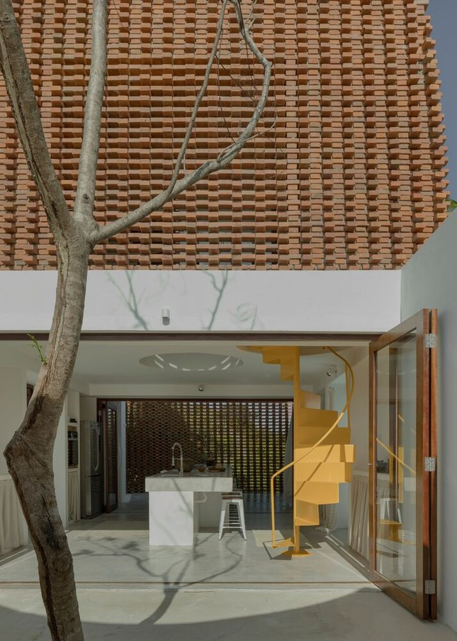 Để đảm bảo tiết kiệm diện tích, một cầu thang xoắn ốc bằng thép màu vàng tươi được sử dụng để đi lên các tầng.