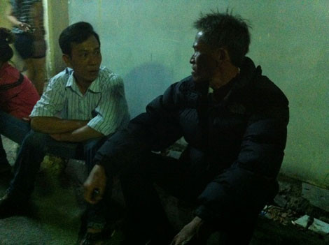 Cha của nạn nhân (áo đen) ngồi thẫn thờ trước nhà xác chờ nhận thi thể con.