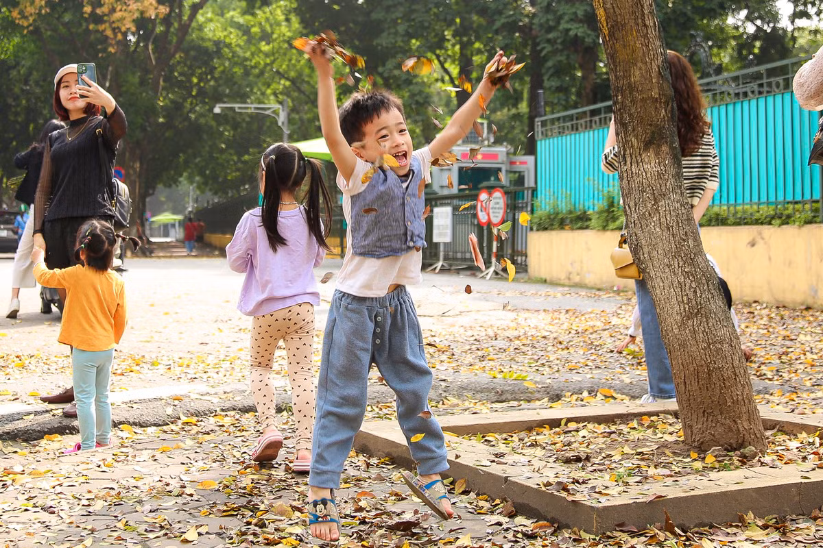 Trẻ em thích thú vui đùa trên con đường trải đầy lá vàng. 
