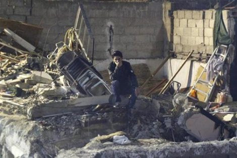 Một người đàn ông Syria ngồi rầu rĩ trên đống đổ nát sau cuộc giao tranh của quân đội chính phủ và quân nổi dậy.