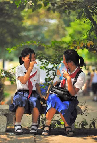 Hai nữ sinh Triều Tiên ngồi trên ghế đá vui đùa cùng nhau.