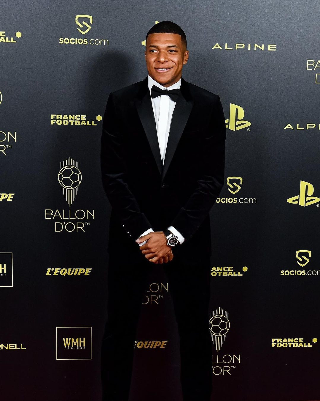 Tại lễ trao giải Quả bóng vàng ở Paris năm 2022, Mbappe chọn sơ mi trắng thắt nơ và set vest nhung, nhấn vào đồng hồ phiên bản giới hạn Hublot.