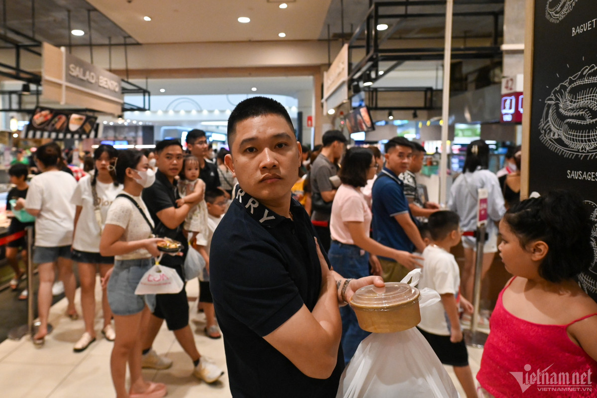Lượng khách từ ngoài tràn vào trung tâm thương mại này mỗi lúc một tăng, người đến sau phải đứng xếp hàng chờ đến lượt vào bàn ăn.