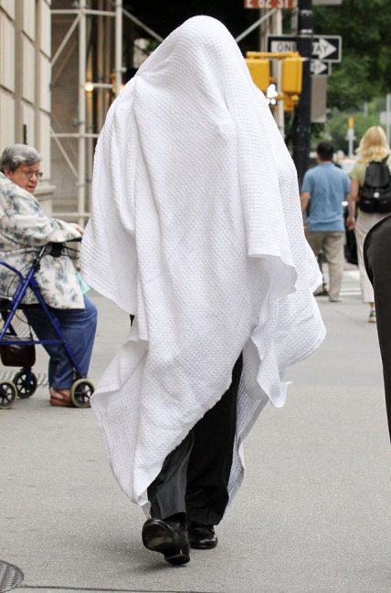 Nam diễn viên người Mỹ Alec Baldwin di chuyển trên phố với chiếc khăn bông lớn trùm lên người.