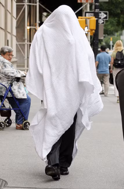 Nam diễn viên người Mỹ Alec Baldwin di chuyển trên phố với chiếc khăn bông lớn trùm lên người.