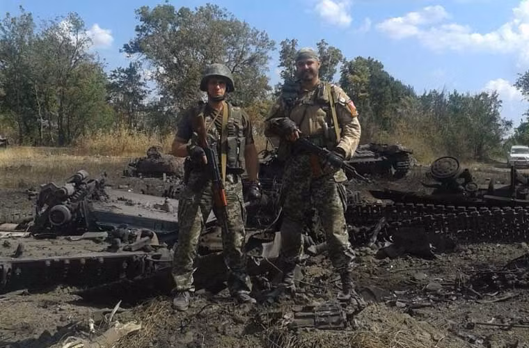 Các chiến binh phe ly khai miền đông đứng trên khu vực đầy xác xe tăng – thiết giáp quân đội Ukraine bị phá tan nát, không còn nhận ra được hình dạng sau một cuộc tấn công.