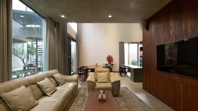 Điểm nhấn mặt tiền là hệ khung cửa sổ lá sách trải dài, vừa gợi nhớ nét kiến trúc nhiệt đới truyền thống, vừa giúp tăng cường đối lưu gió cho các không gian bên trong. Phòng khách là tổng hòa của thiết kế hiện đại và phong cách nhiệt đới Á Đông.