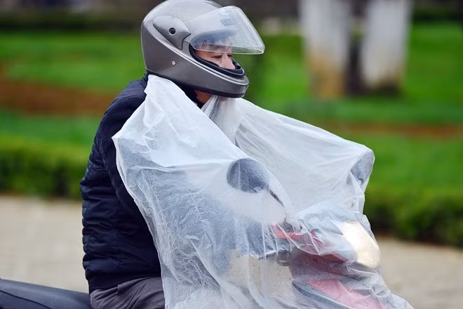 Một số người đi xe máy phải khoác thêm áo mưa để chống lạnh.