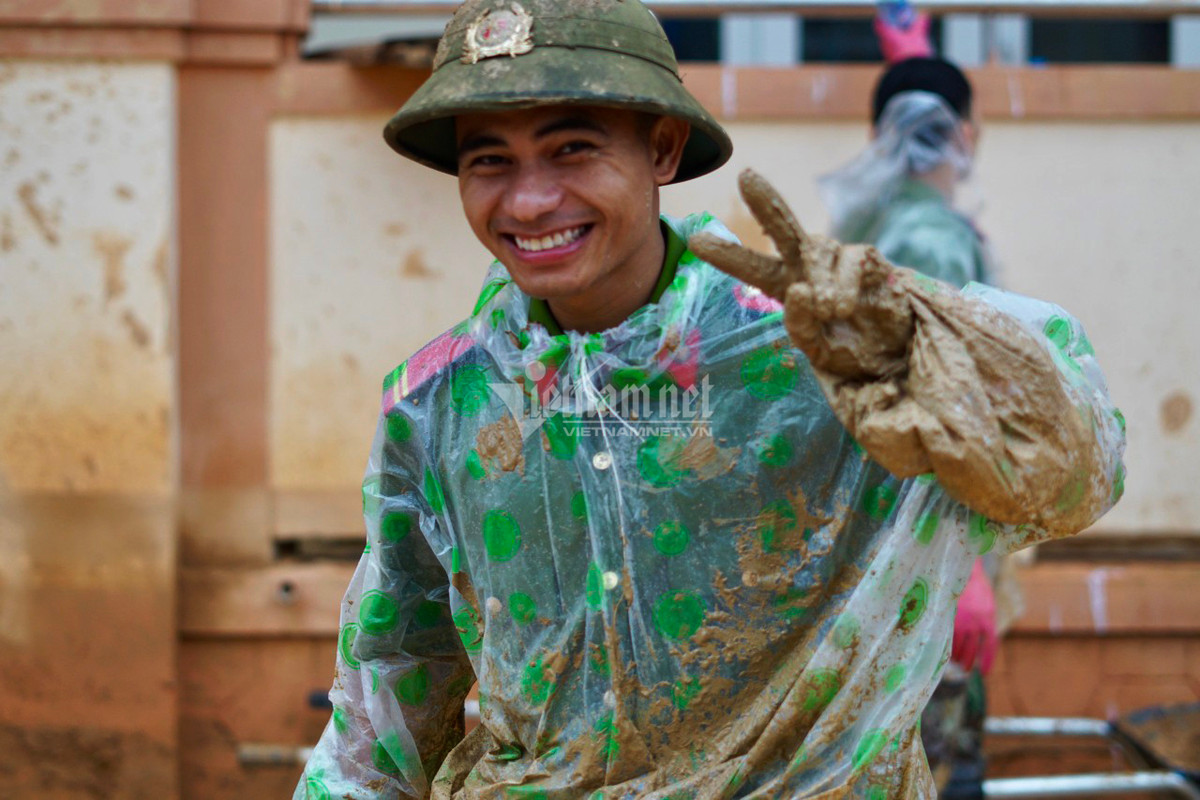 Chân tay lấm bùn chiến sĩ Hồ Văn Long nở nụ cười tươi, không ngại khó khăn.