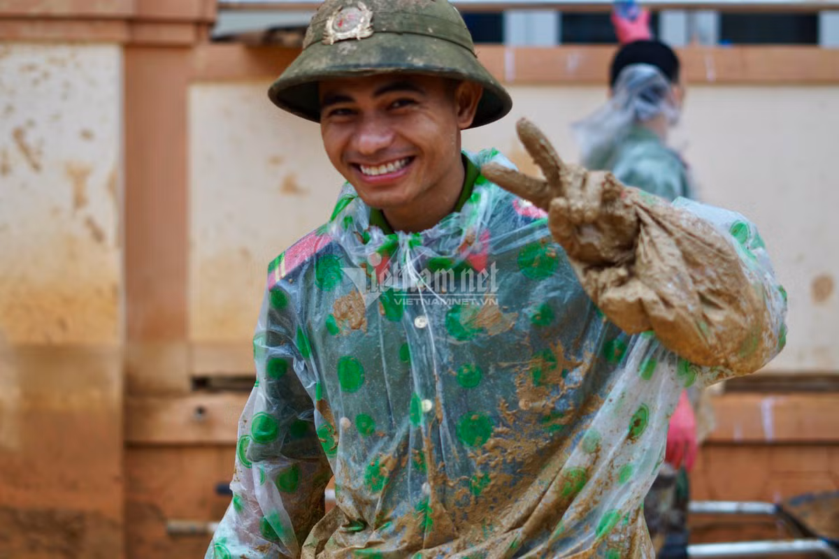 Chân tay lấm bùn chiến sĩ Hồ Văn Long nở nụ cười tươi, không ngại khó khăn.