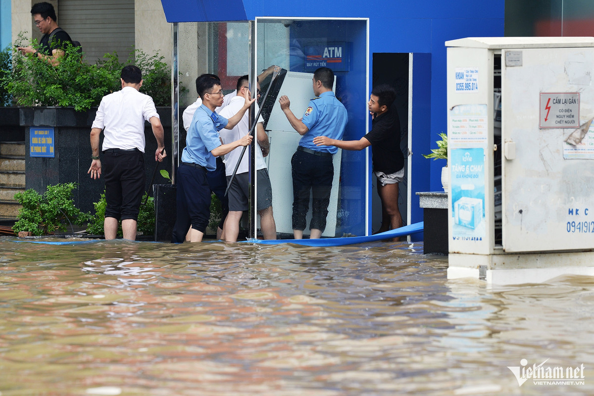Các nhân viên một ngân hàng tìm cách kê cao cây rút tiền tự động để tránh hỏng.