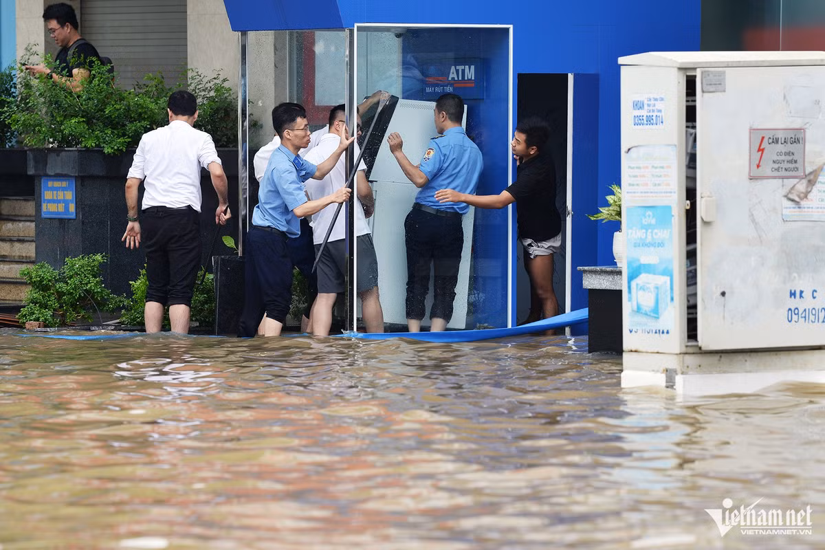 Các nhân viên một ngân hàng tìm cách kê cao cây rút tiền tự động để tránh hỏng.