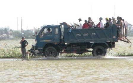 Một chiếc xe tải đang tăng bo xe máy và người đi qua những con đường ngập nước vì bão.