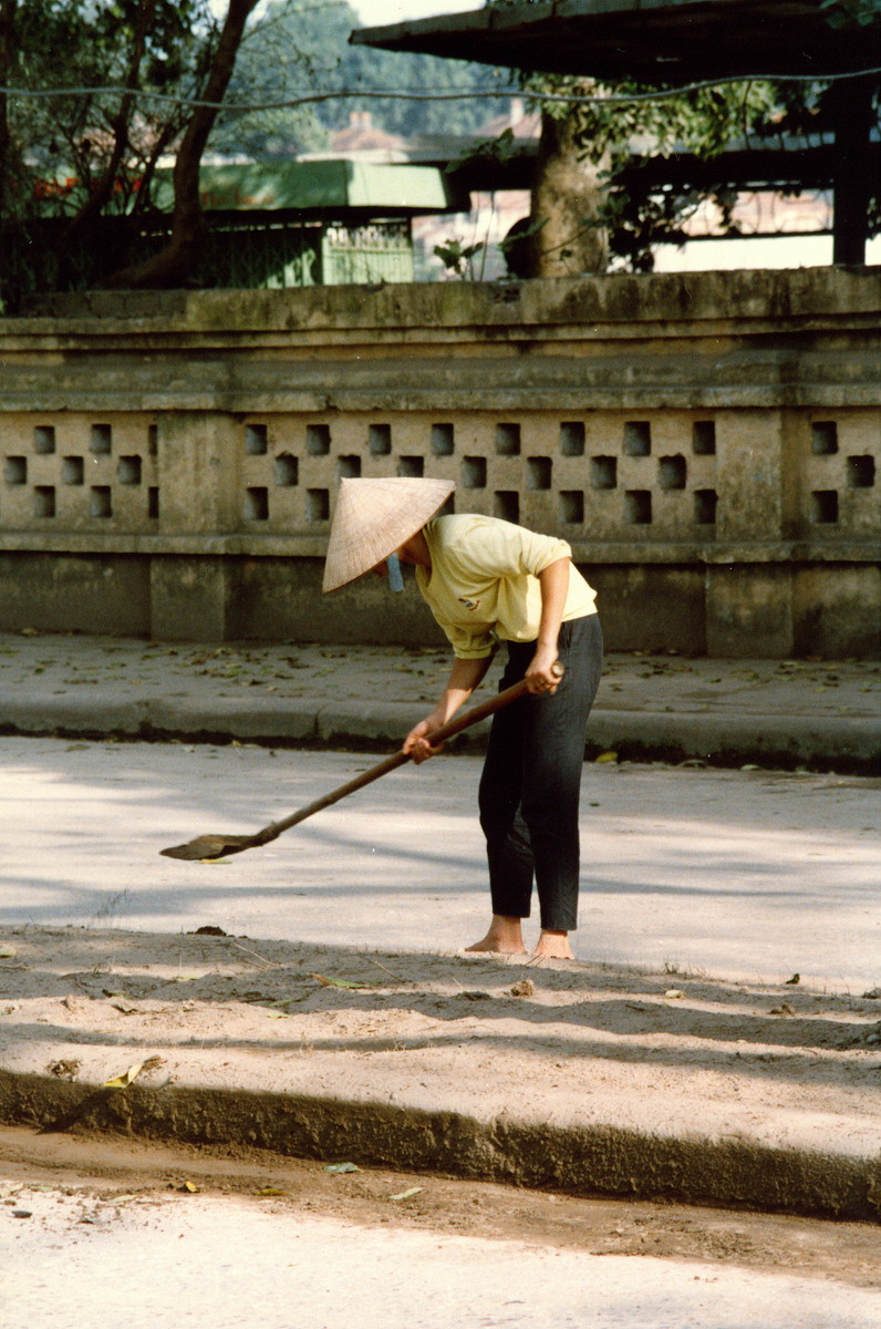 Người lao công quét rác trên đường, phía ngoài nhà hàng bánh tôm hồ Tây.