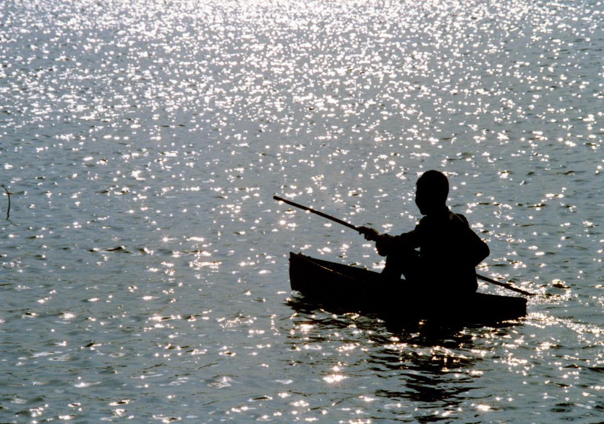 Cậu bé chèo thuyền thúng trên hồ.