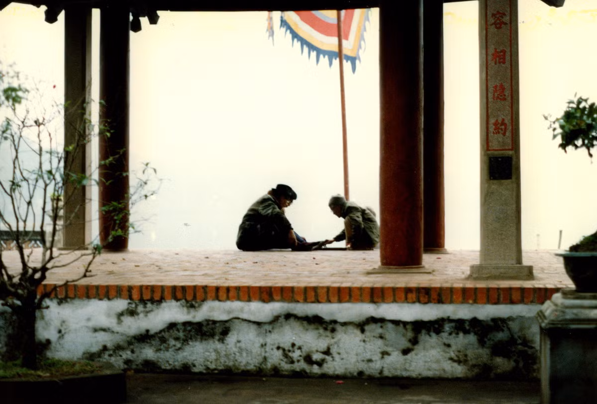 Đình Trấn Ba nhìn từ sân đền Ngọc Sơn. Hai cụ ông đang đánh cờ tướng ở đây.