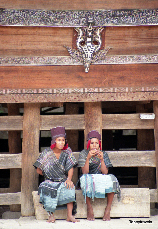 Hai nam giới người Batak Toba ngồi bên ngoài nhà sàn.