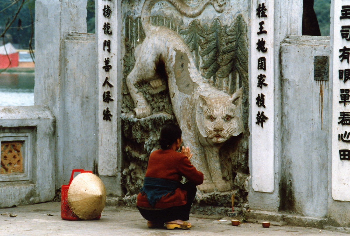 Một người phụ nữ cầu khấn trước tượng bạch hổ ở cổng Long Môn - Hổ Bảng ở lối vào đền Ngọc Sơn, Hà Nội năm 1990. Ảnh: Diligam_te Flickr.