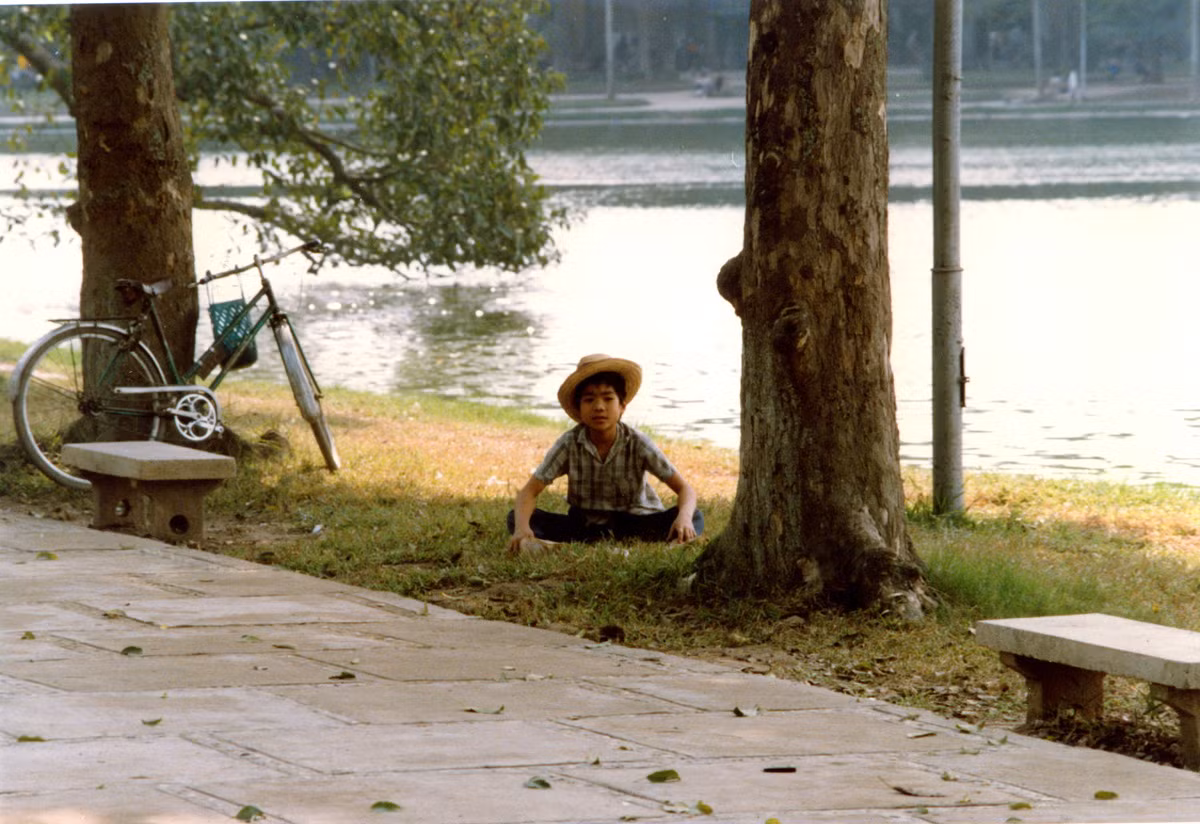 Cậu bé thư giãn trên bãi cỏ bờ hồ.