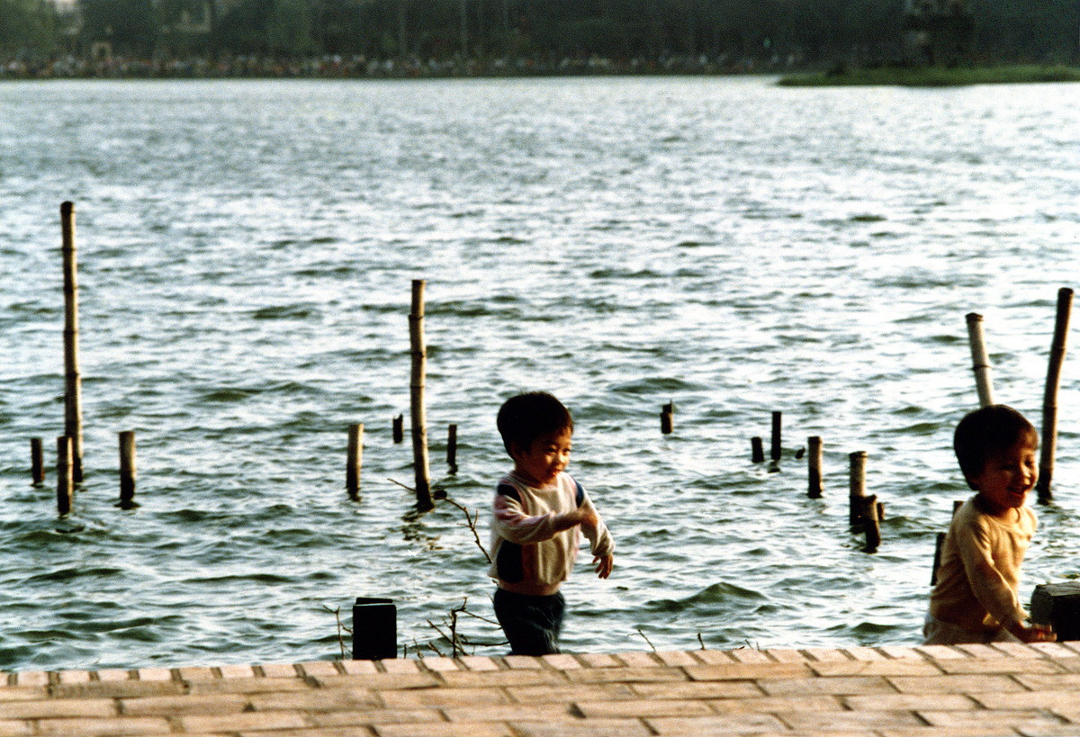 Hai em nhỏ chơi đùa ở bờ hồ.