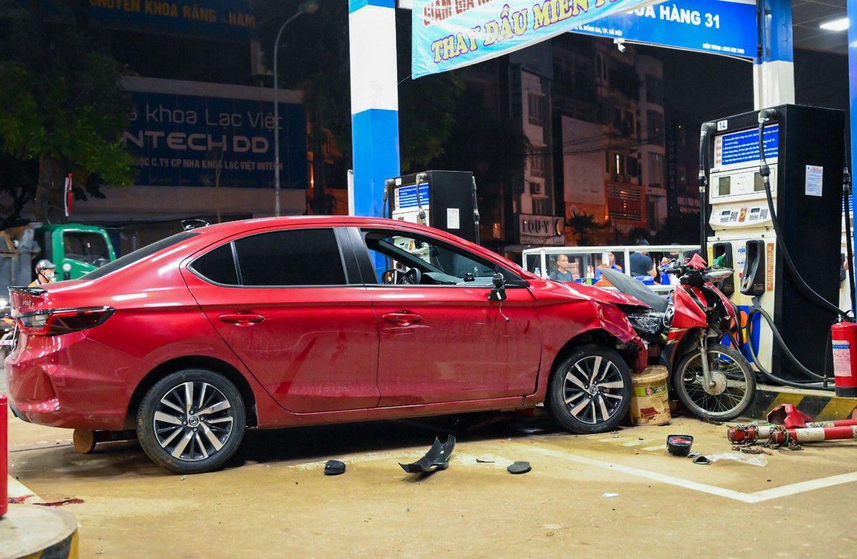 Do lực đâm quá mạnh, một chiếc xe máy bị kẹp giữa phần đầu ôtô và một cột bơm xăng.