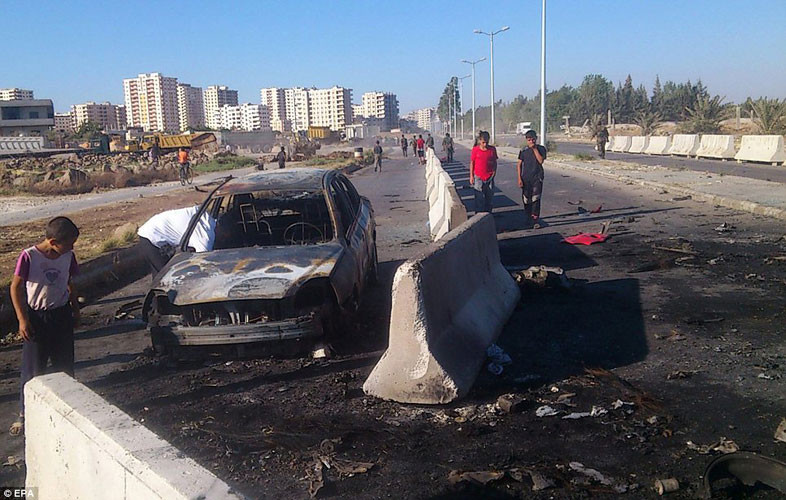 Chiếc xe hơi trúng bom đạn, cháy rụi, nằm trơ lại trên đường phố vắng vẻ.