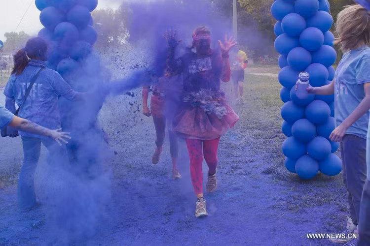 Một thiếu nữ bị phun bột màu xanh đầy người.