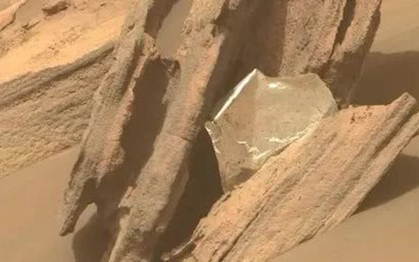 Trong hình ảnh, có thể thấy một phần của tấm chăn chống nhiệt, vốn được sử dụng để bảo vệ robot khỏi nhiệt độ khắc nghiệt mà nó phải trải qua khi hạ cánh, bị mắc kẹt trong một hốc đá trên bề mặt sao Hoả.