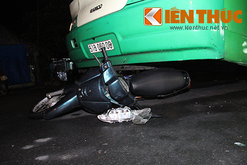 Chiếc xe máy nằm gọn dưới gầm xe buýt, đầu và đuôi xe bị hư hỏng.