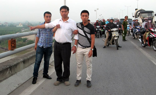 Ông Tường áo trắng (đứng giữa) được cơ quan CSĐT dẫn giải ra cầu Thanh Trì để thực nghiệm lại hiện trường